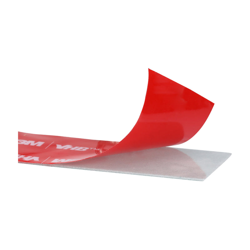 Close-up of 3M VHB Max-060GF double-sided acrylic foam tape with red liner partially lifted to reveal gray adhesive.