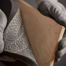 Detailed view of foam bonded to wood using hot melt spray adhesive for industrial assembly.