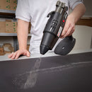 A swirl pattern of adhesive is applied during active use of the Tec 6300 pneumatic spray glue gun in a workshop setting.