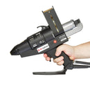 The Power Adhesives Tec 7300 spray glue gun shown held in one hand, displaying the trigger, grip, and integrated stand.